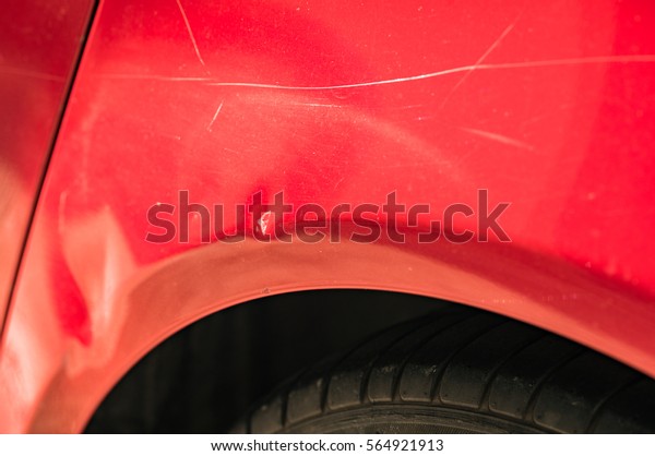 Car body damage, dents and scratches on the red\
car paint.