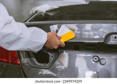 car body painter painting select paint colors using sample card for pick choice color shade in auto garage body workshop - Powered by Shutterstock