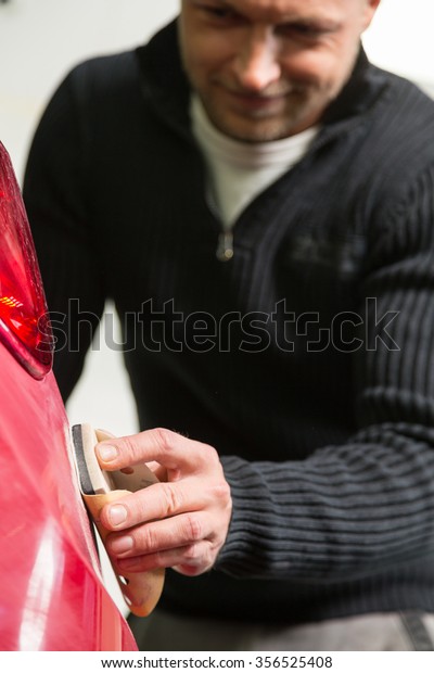 Car body\
painter preparing varnish with a\
sandpaper