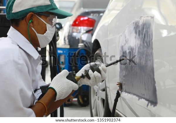 Car body repair by skilled technicians are repairing
car paint with power tools That wear protective equipment, safety
glasses, gloves, nose pads, hats to prevent accidents that may
occur During work