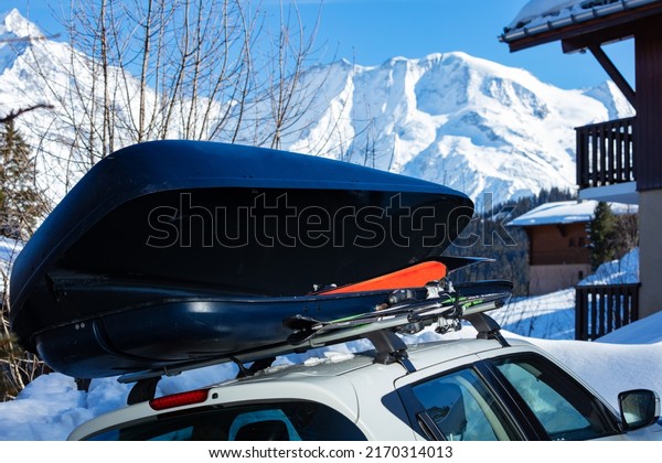 Car box on the roof of the vehicle with ski inside\
over the mountain peaks