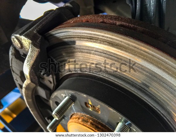 Car brake disc without wheel closeup waiting for\
repairs. Close up disc\
brake.