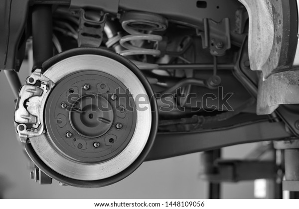 Car brake part at\
garage,car brake disc without wheels.Suspension of car in car\
service center.Close up.   