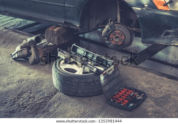 Car brake repairing\
in garage, Brakes on a car with removed wheel, car brake part at\
garage,car brake disc without wheels. old automobile is under\
repair. Maintenance wheels.