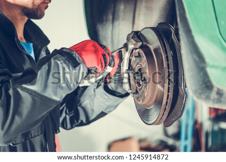 Car Brakes Servicing by Caucasian Vehicle Mechanic in His 30s. Automotive Industry.

