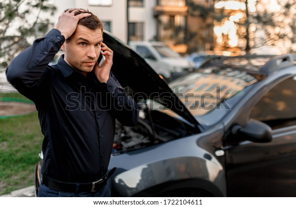 Car breakdown concept. The car will\
not start. A young man is calling for a car service. They cannot\
fix the car on their own. Insurance must cover all\
costs.
