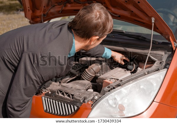 Car\
breakdown. Confused man stands with open\
hood.