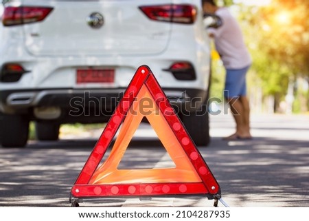 Car breakdown on road. Car broken down with red emergency stop sign warning triangle on the road.
Young man maintenance, fixing car accident on street. mechanic checking car engine.