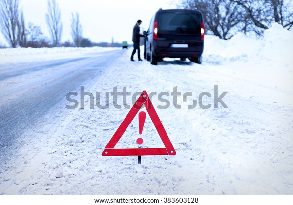 Car breakdown with red triangle on snowy winter\
road, outdoor