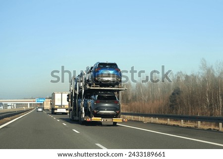 car breakdown and towing on a country road. A tow truck is transporting a damaged car that was involved in a traffic accident. The car owner is calling for assistance