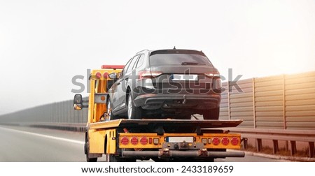 Car breakdown and towing. A tow truck with a broken car on a speedway road. Towtruck transporting a car on the highway. Car service transportation concept