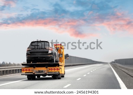 Car breakdown and towing. A tow truck with a broken car on a speedway road. Towtruck transporting a car on the highway. Car service transportation concept