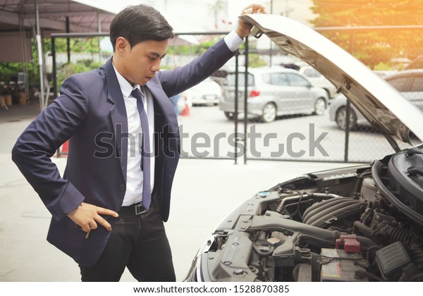 Car\
broke down, Business man in suit open car bonnet or Hood of car and\
looking for a malfunction .                         \
