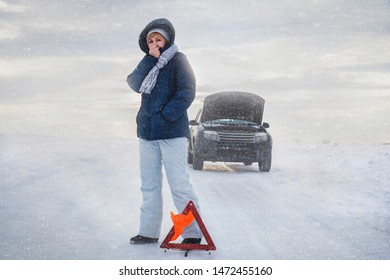 The Car Broke Down On The Road. The Woman Warms Her Cold Hands. She's Cold. Winter. Emergency Stop Sign. Around A Snowy Field.