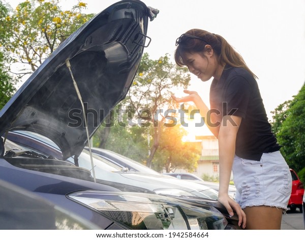 The car broke down, smokes from under the hood,\
the driver shocked,Caucasian female having a problem with white car\
on a roadtrip.