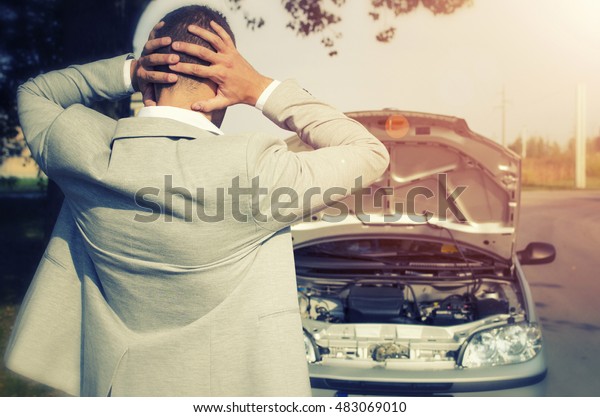 Car broke. Man\
looking at the broken car not knowing what to do. Car service. Tow\
service. Car breakdown.