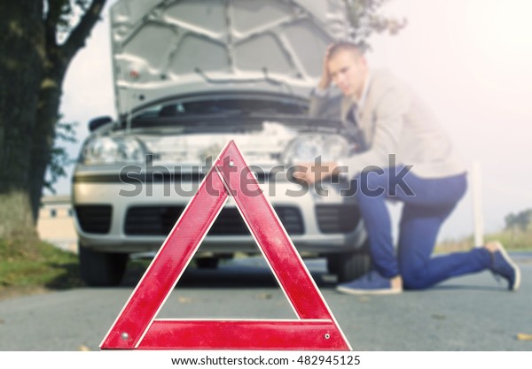 Car broke. Man standing on the\
road by the broken car. Tow service needed. Car break\
down.