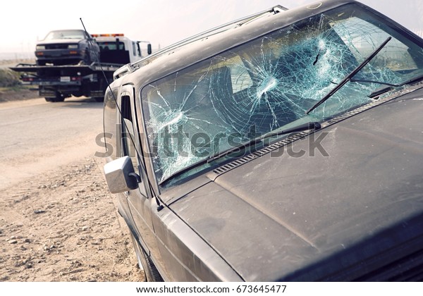 Car with broken\
windshield on roadside