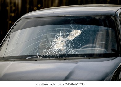 A car with a broken windshield on a spring day