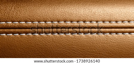 Car brown leather interior. Part of perforated leather door handle details. Orange Perforated leather texture background. Texture, artificial leather with stitching. 