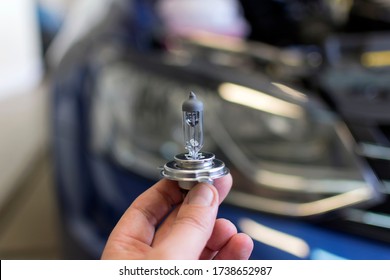 Car Bulb In Hand On A Background Of A Car Headlight. Car Repair.