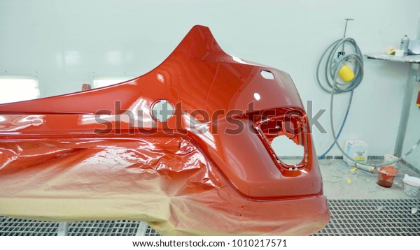 Car\
bumper after painting in a cars spray booth. Auto vehicle cherry\
color bumper. Parts of car in cars spray\
booth.
