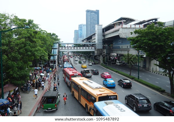 Car and bus on the\
road with people at footbridge and bus terminal in Bangkok Thailand\
in summer May 2018