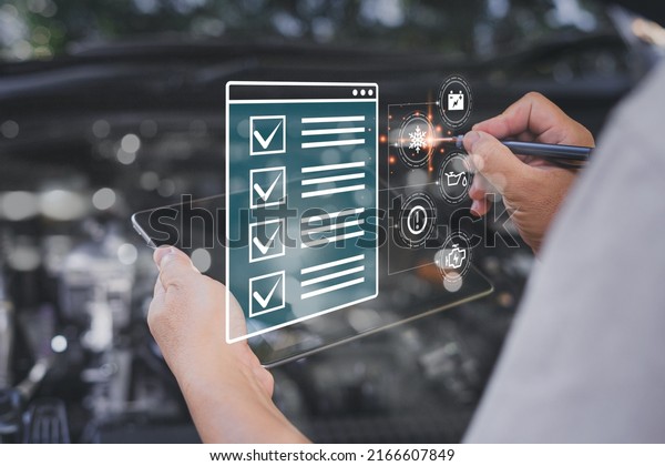 Car business concept and technology on virtual\
screen, Serviceman use tablet check item list of car mileage for\
maintenance and service with the engine room in the\
background,Smart work of car\
service