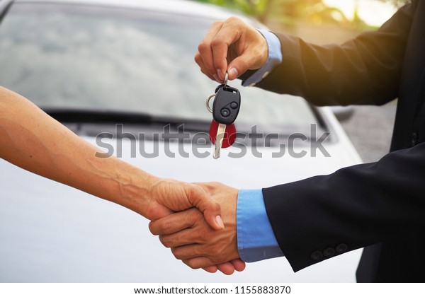 Car buyers are taking car keys from car owners.\
Buy sell and rent concept
