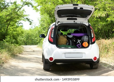 Car With Camping Equipment In Trunk On Forest Road. Space For Text