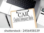 CAR - CAPITAL ADEQUACY RATIO word on clipboard on a laptop with calculator and pen . 