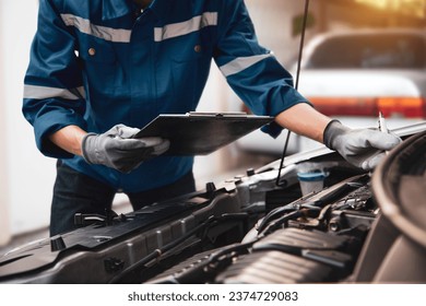 Car care maintenance and servicing, Hand technician auto mechanic checking inspection list after fix or repairing change spare part car engine problem and car insurance service support assistance.