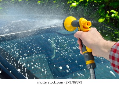 Car Care - Man Washing A Car Using A Garden Spray Gun