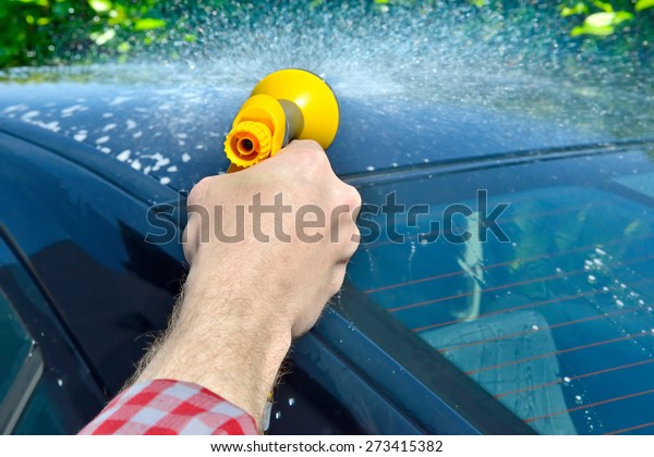 Car\
Care - Man washing a car using a garden spray\
gun