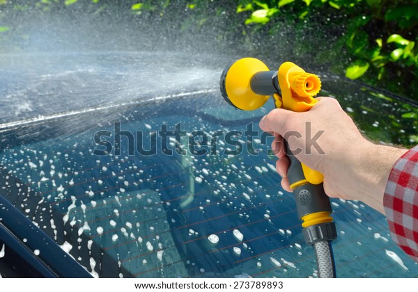 Car\
Care - Man washing a car using a garden spray\
gun