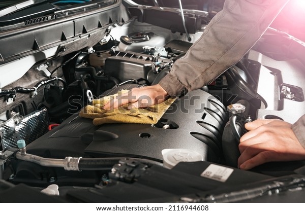 Car care. The mechanic wipes the dust under the hood\
of the car.