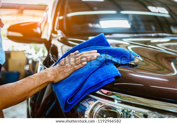 Car care service worker used microfiber cloth cleaning\
outside car 