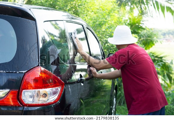 A car care service worker\
is washing, wiping or polishing outside of car. Concept :  Car\
cleaning maintenance. Hobby and pastime activity. Outdoors\
servicing.