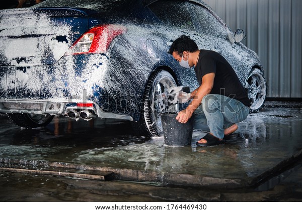 Car care staff cleaning (clean, wash, polish,\
wax and glass coating) the car (Car detailing) at car care shop in\
Bangkok Thailand