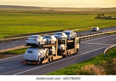 Car carrier trailer transports cars on highway on sunset background. Auto transport and car shipping services concept. Truck with Semi-remorque. Cars Shipping. BELARUS - SEPT 15, 2020