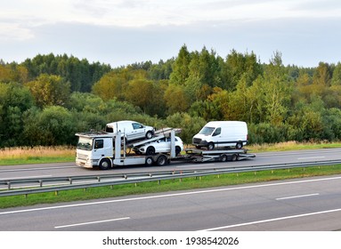 Car carrier trailer transports cars on highway on sunset background. Auto transport and car shipping services concept. Truck with Semi-remorque. Cars Shipping