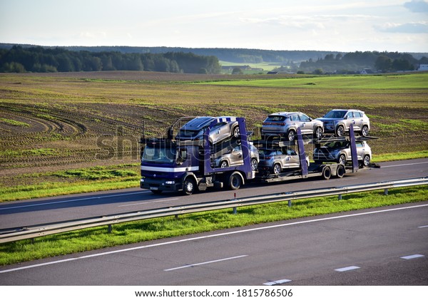 Car\
carrier trailer transports cars on highway on sunset background.\
Auto transport and car shipping services concept. Truck with\
Semi-remorque. Cars Shipping. BELARUS - SEPT 15,\
2020