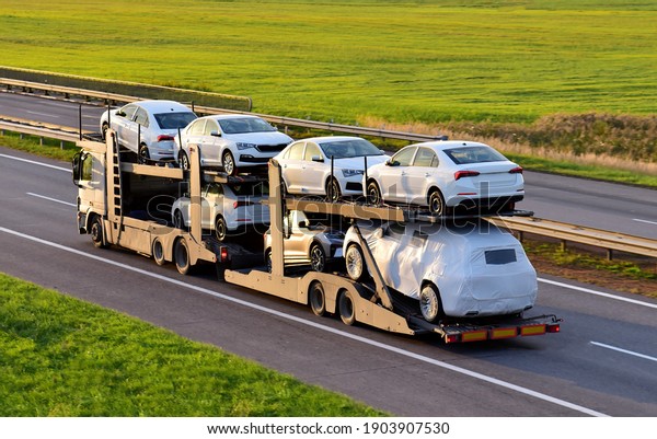 Car\
carrier trailer transports cars on highway on sunset background.\
Auto transport and car shipping services concept. Truck with\
Semi-remorque. Cars Shipping. Car\
transportation