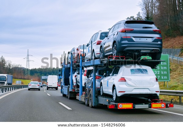 Car carrier transporter truck on road. Auto\
vehicles hauler on driveway. European transport logistics at\
haulage work transportation. Heavy haul trailer with driver on\
highway.