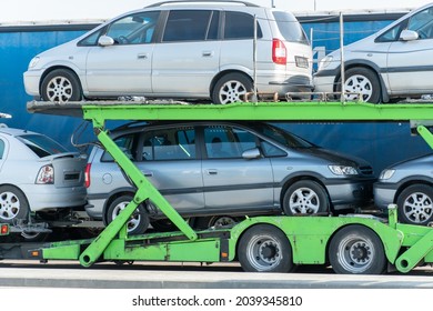 A Car Carrier With A Two-level Adjustable Hydraulic Semi-trailer In The Parking Lot. Transportation Of New Passenger Cars On A Cargo Trailer. Profitable Purchase Of New Cars.