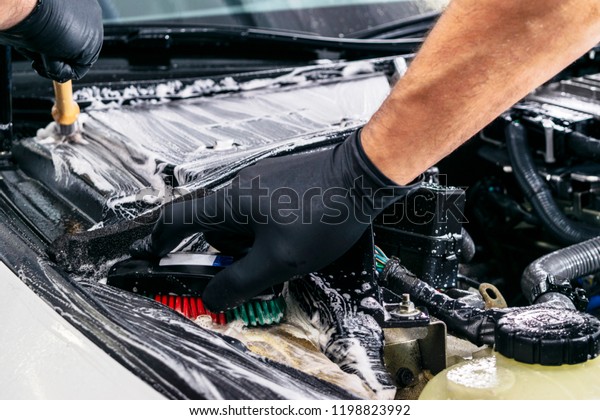 Car in a\
carwash. Wash with foam in wash station. Carwash. Washing at the\
station. Car washing concept. Car detailing. A man cleaning car.\
Cleaning engine with the foam and\
brush