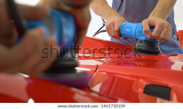 In the car center (in\
the garage), professionals polish a new sports car. Luxury car\
polishing. Concept of: Racing, Sport car, New, Slow motion, Nascar,\
Red, Chrome plated.