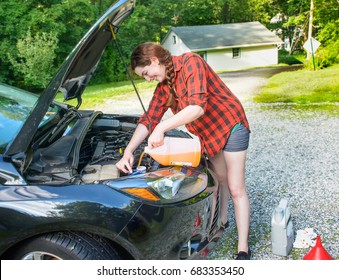 Car Checkup In Preparation For Road Trip.  Young Woman Adds Windshield Wiper Fluid.