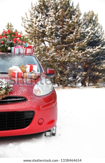 Car with Christmas tree, wreath and
gifts in snowy forest on winter day. Space for
text