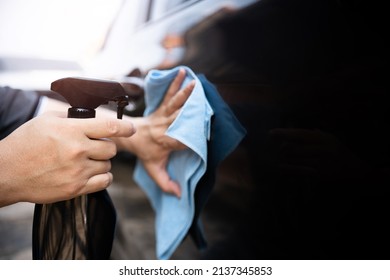 Car Clean Concept, Hand A Man Holding Clean Spray Wax And Microfiber Clenning Car Body Cloth To Take Care Of The Surface Of The Car From Washing 